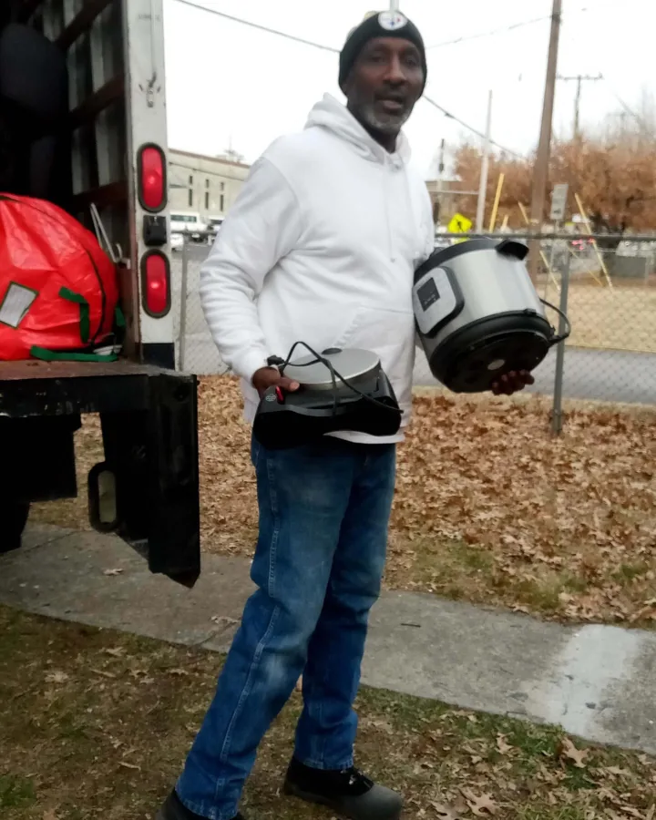 Junkdrop crew member holding two small kitchen appliances beside a truck