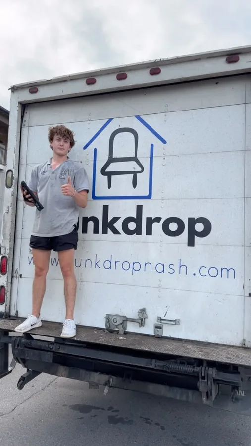 Crew member on the lift at the rear of a Junkdrop truck