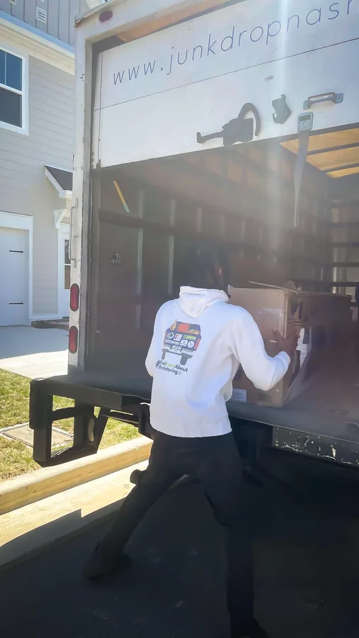 Crew member loading a large item into a Junkdrop box truck